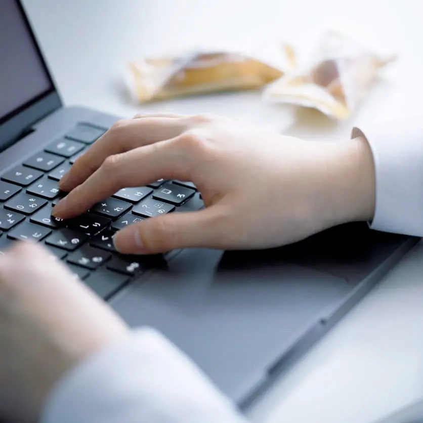 パソコンを操作する手元と焼き菓子